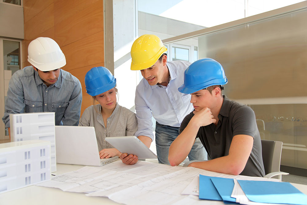 men in hard hats looking at a laptop